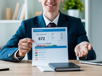 selective-focus-of-cheerful-man-holding-document-with-credit-report-lettering-near-laptop-in-office-stockpack-deposit-photos-scaled